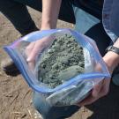 Researcher holds bag of rock dust to be added to agricultural soils. 