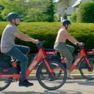 Two people ride red Spin bicycles.
