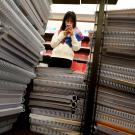 Person seen through stack of notebooks, scanning phone