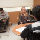 Students sit around desks talking to their professor at UC Davis. 