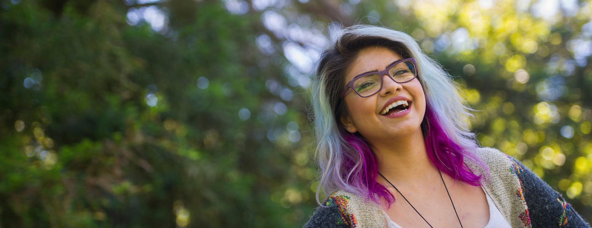 A female student with multicolored hair smiles on the UC Davis quad