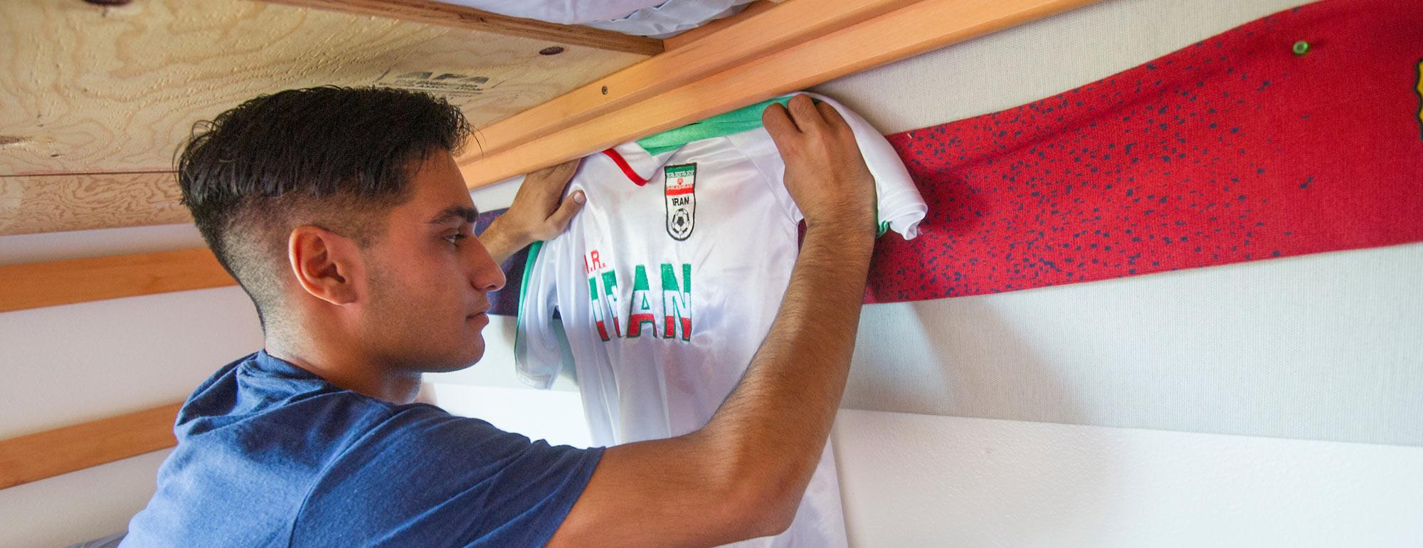 A student pins up an Iranian National Soccer team jersey in his dorm room