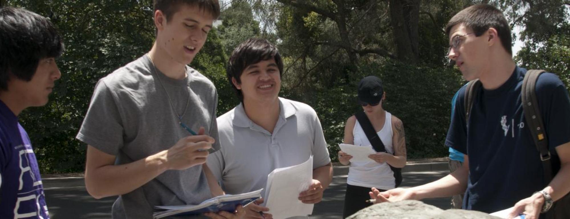 uc davis students talk and hold papers in a group