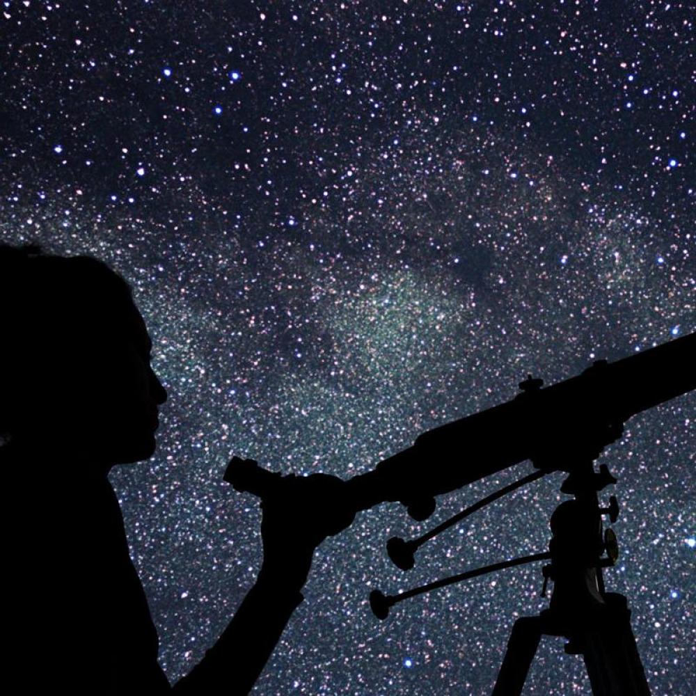A person looking up at the stars through a telescope