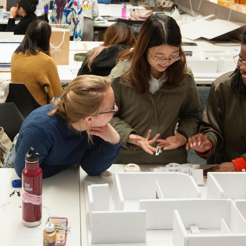 Three female students discussing a design model
