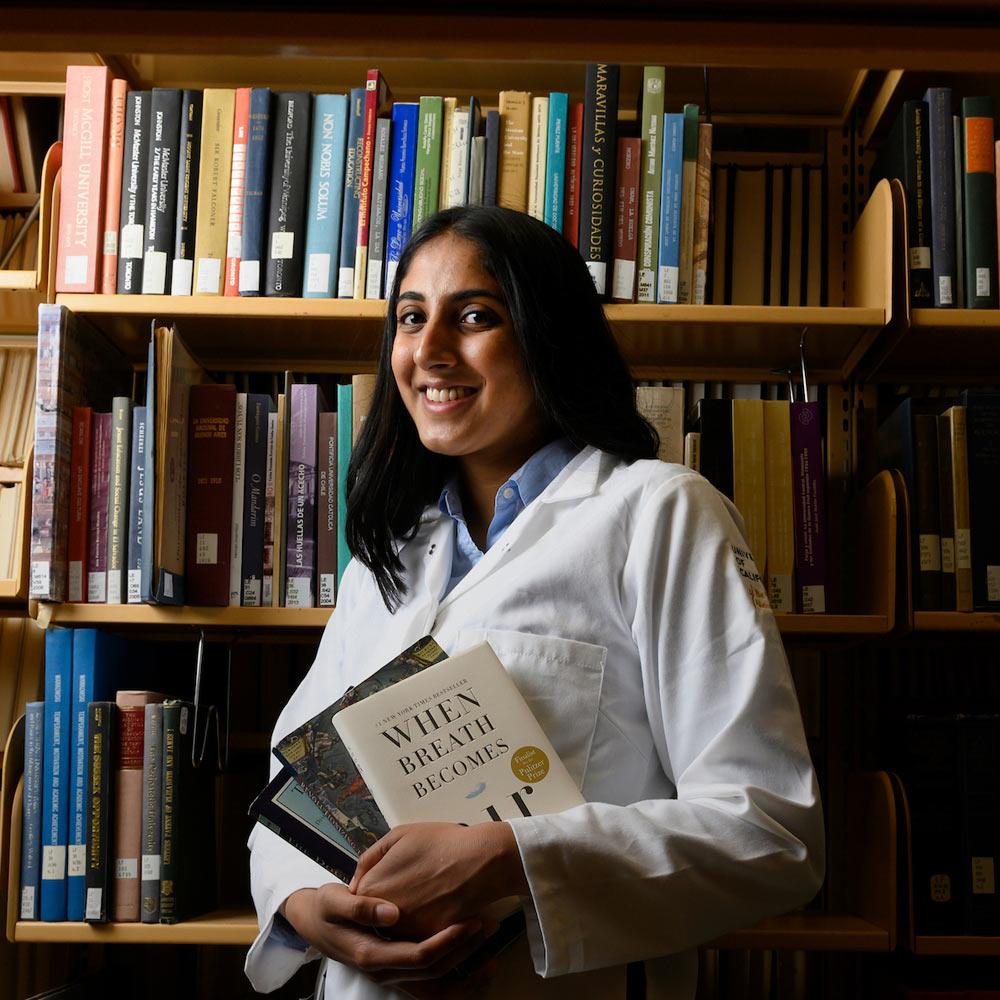A scholarship winning student poses in the library with her favorite books.