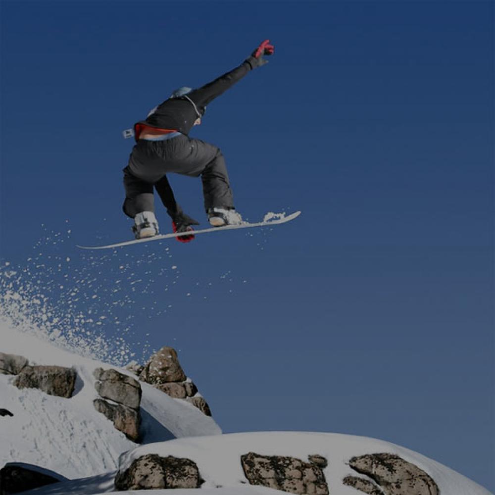 A snowboarder sending it off a mountain top