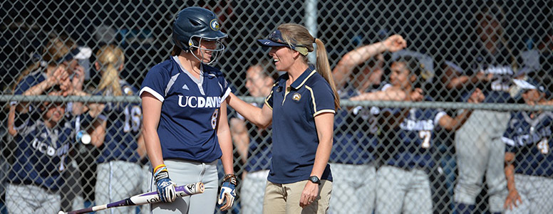 A softball coach, right, talking to a batter in a helmet