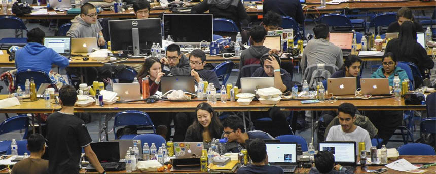 Students crowd tables to work together at computer stations