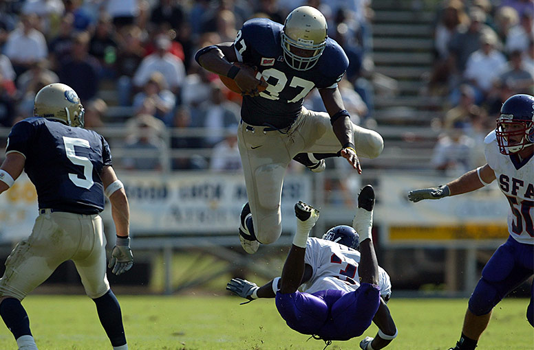 Football player Daniel Fells leaping over a player