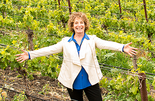 Photo of Kathy Joseph in the middle of her vineyard with her arms held wide