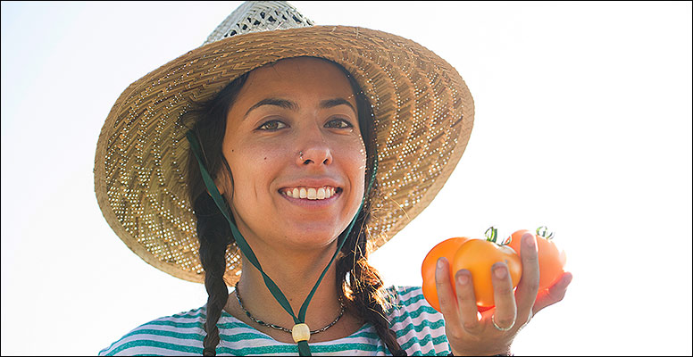 Young woman in a straw hat holding a big tomato