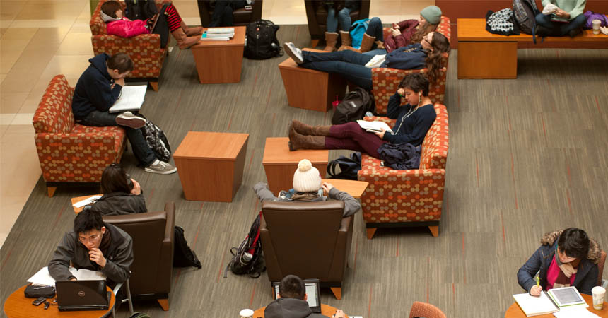 Students occupy tables and couches in building's lobby