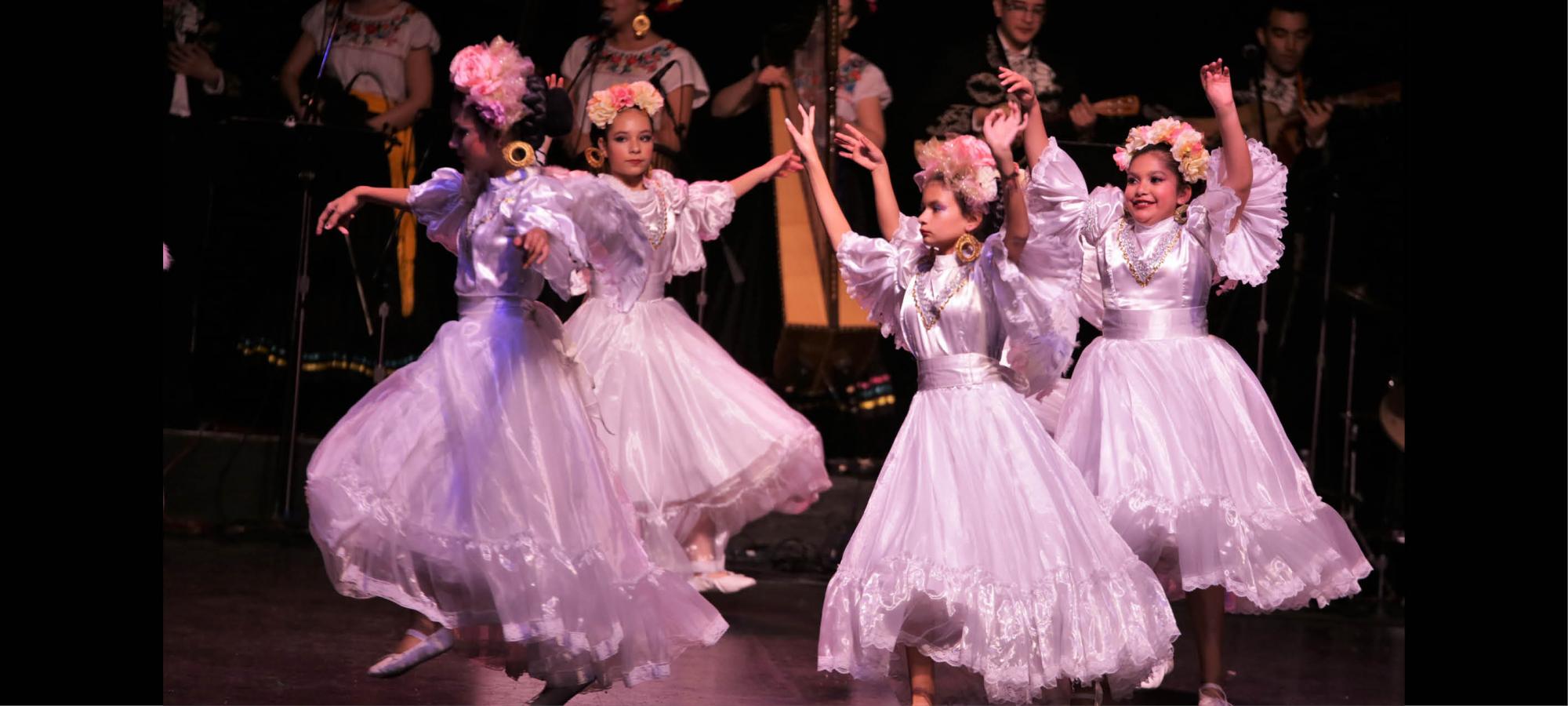 Four young ballerinas dancing on stage.