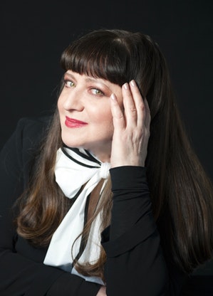 A portrait photograph of Basia holding her hand up against the side of her face.