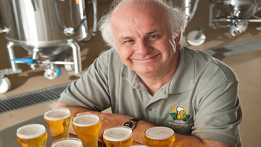 Man sits with arms crossed behind row of full beer glasses