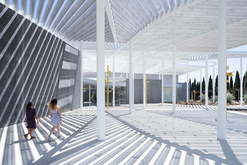 Two women walk under the canopy of the Shrem Museum