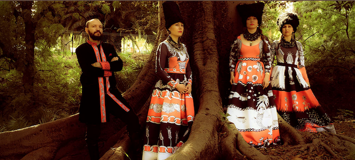 A photo of the band members standing in a forest and wearing colorful Ukrainian garb.