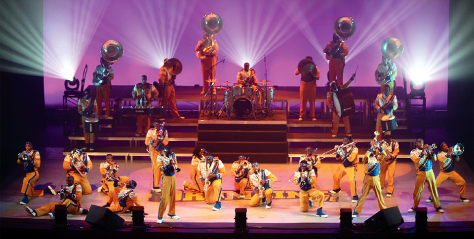 Approximately 30 members of the Drumline Spectacular performing on stage.