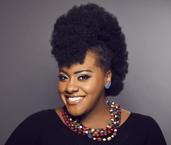A portrait of Etana in front of a gray background.