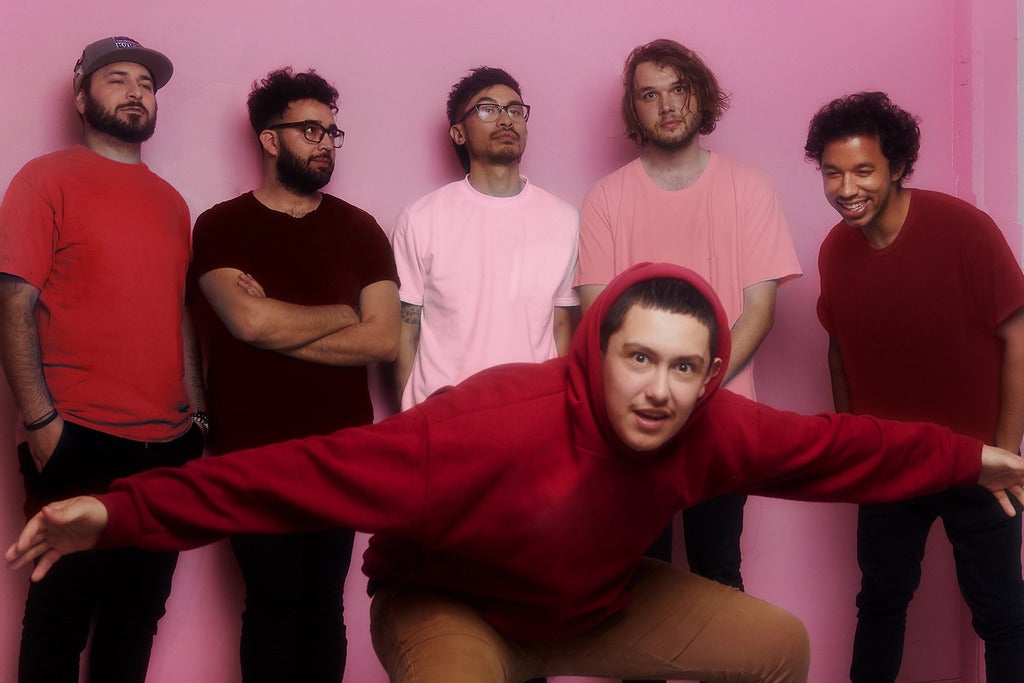 A photo of the group in front of a pink wall.