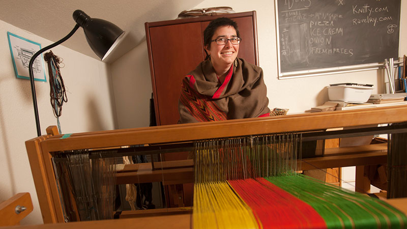 A woman sits at a loom