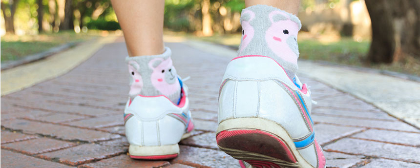 Woman's feet in running shoes take small step forward on brick walkway.