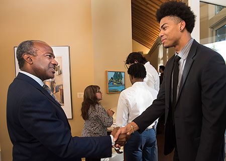UC Davis Chancellor-designate welcomes a male student to the Chancellor's Residence