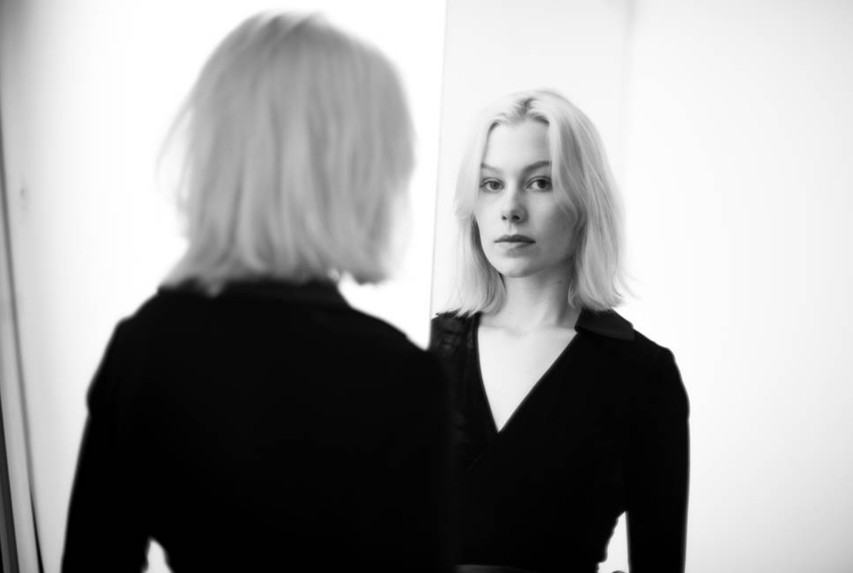 A photo of Phoebe Bridgers looking in a mirror.
