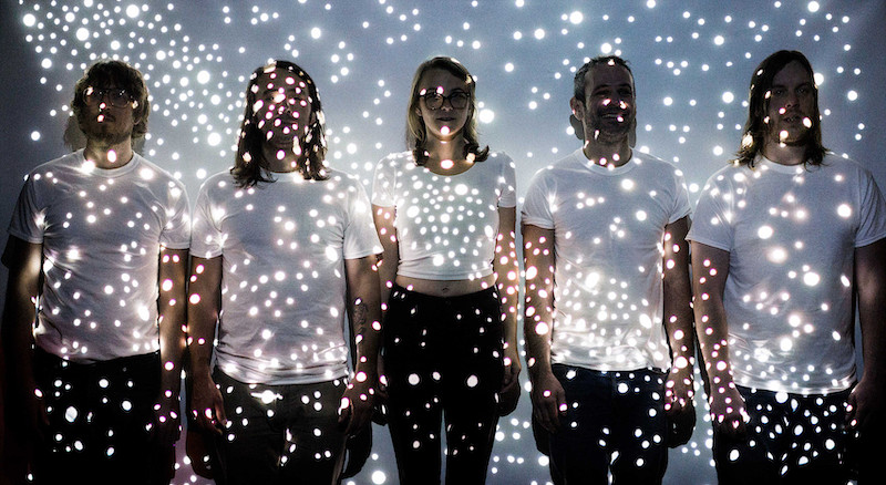 The members of the Deer photographed in dim light with tiny dots of light projected on them.